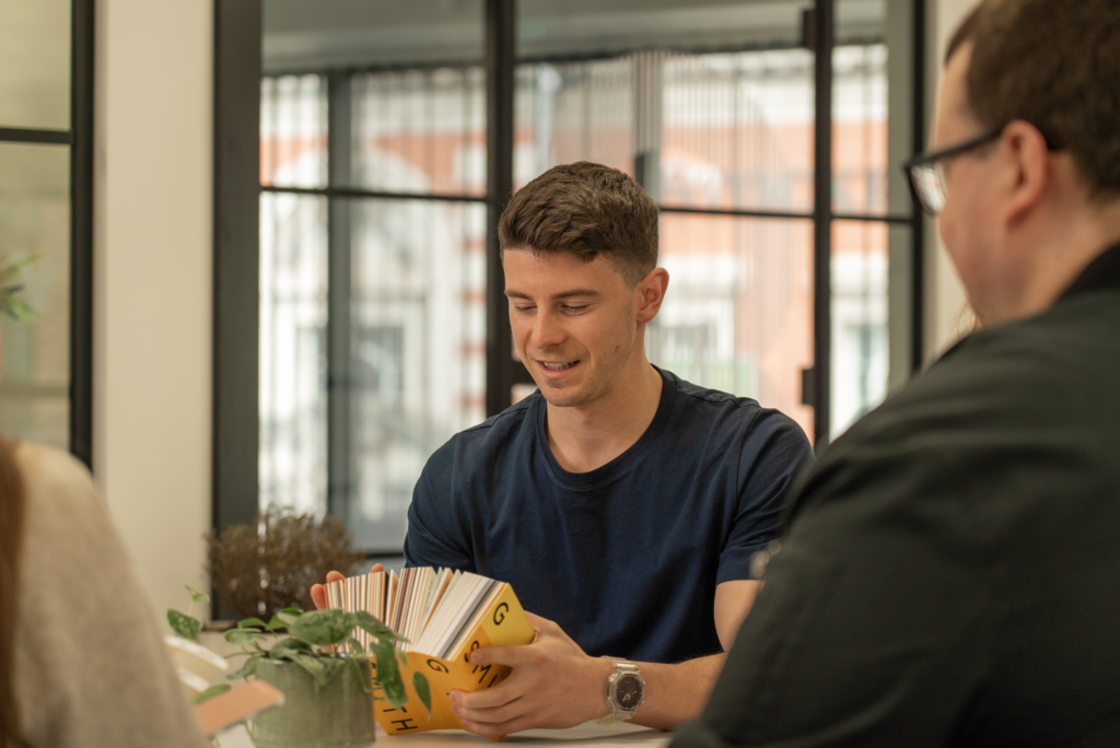 Create8 brand designer looking through a Pantone Book with colleagues for a rebrand project