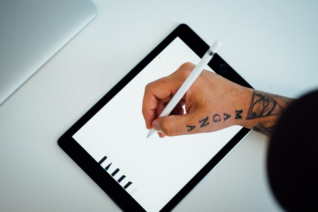 Man with tattoos drawing on an iPad with a stylus for a rebrand project