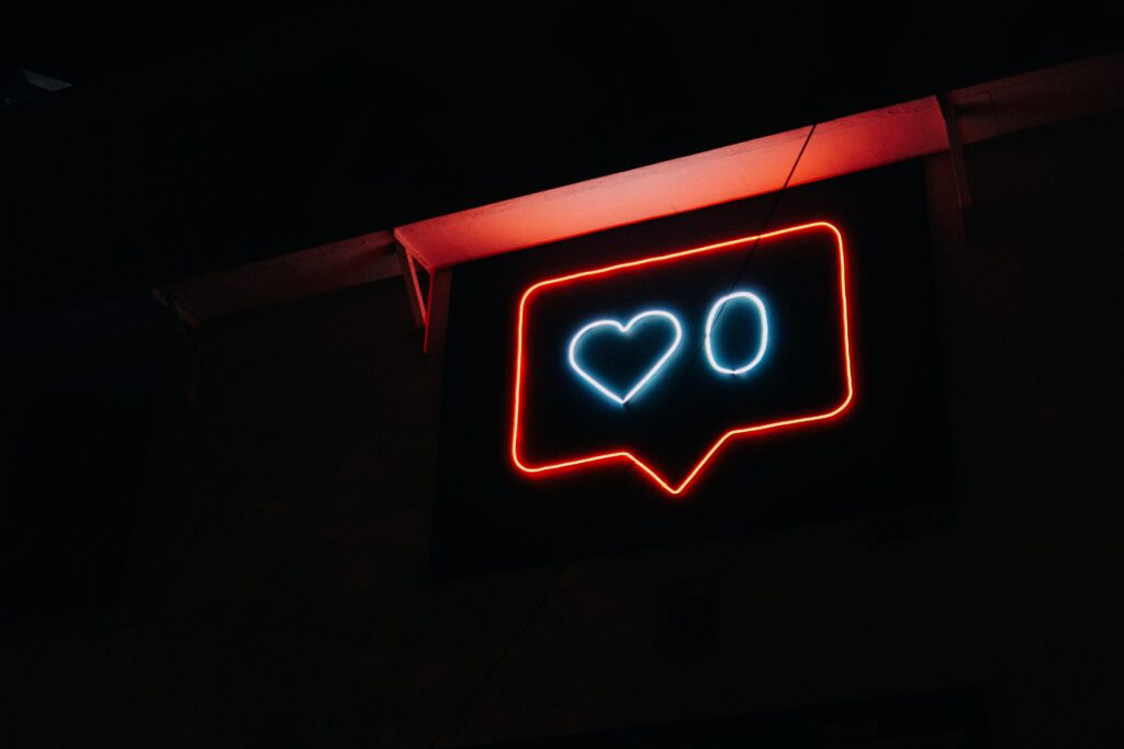 Social media like and share symbol in a neon sign on a black background