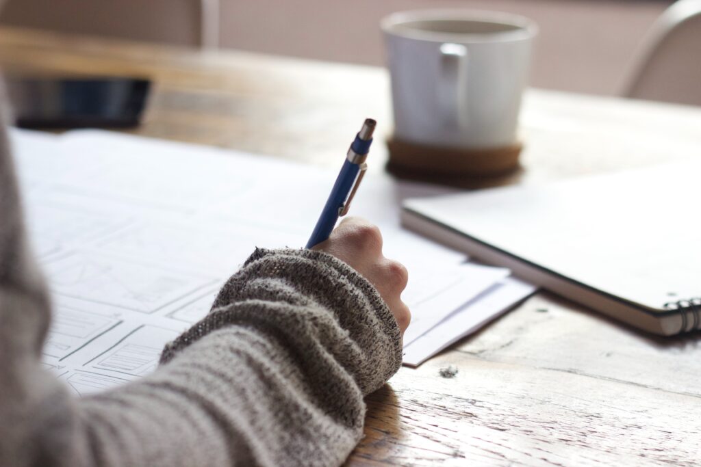 Close up of woman's hand writing a blog at her desk