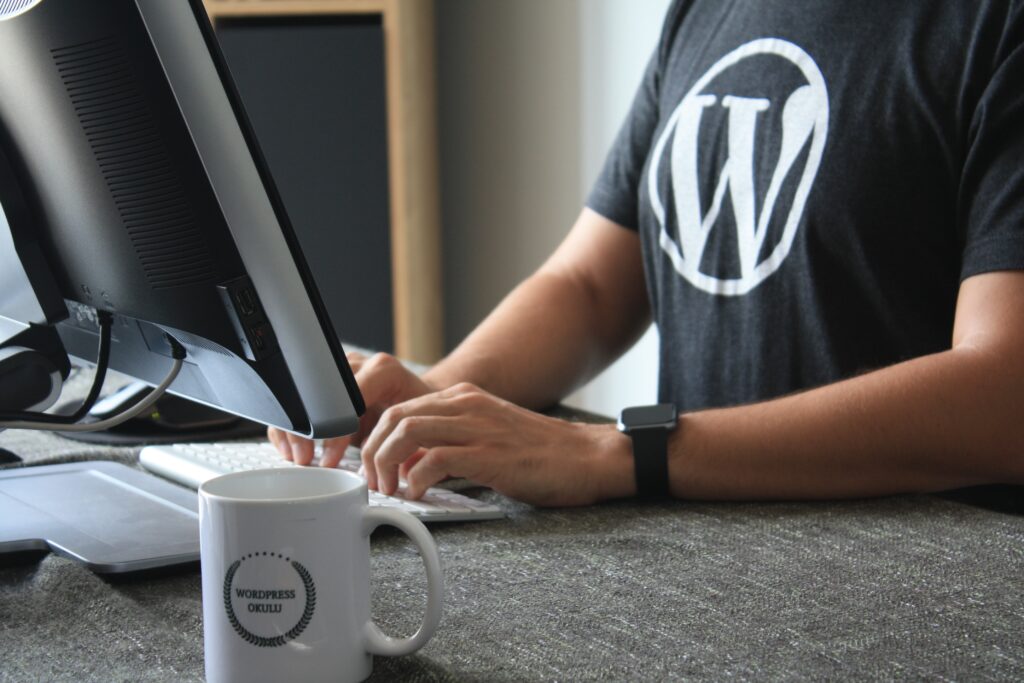 Man wearing a WordPress t-shirt sat at a desk typing