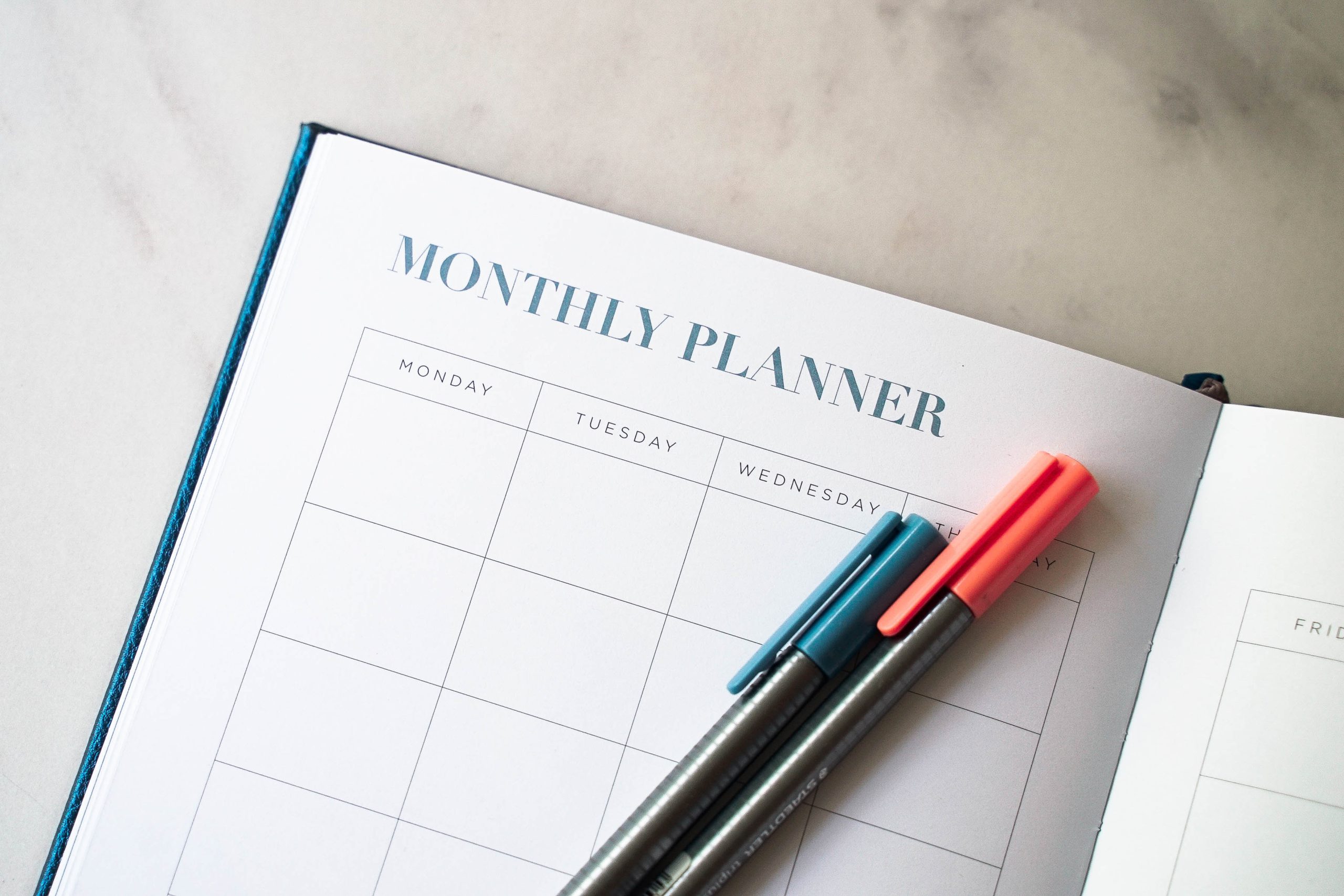 Monthly planner calendar on a desk with pens