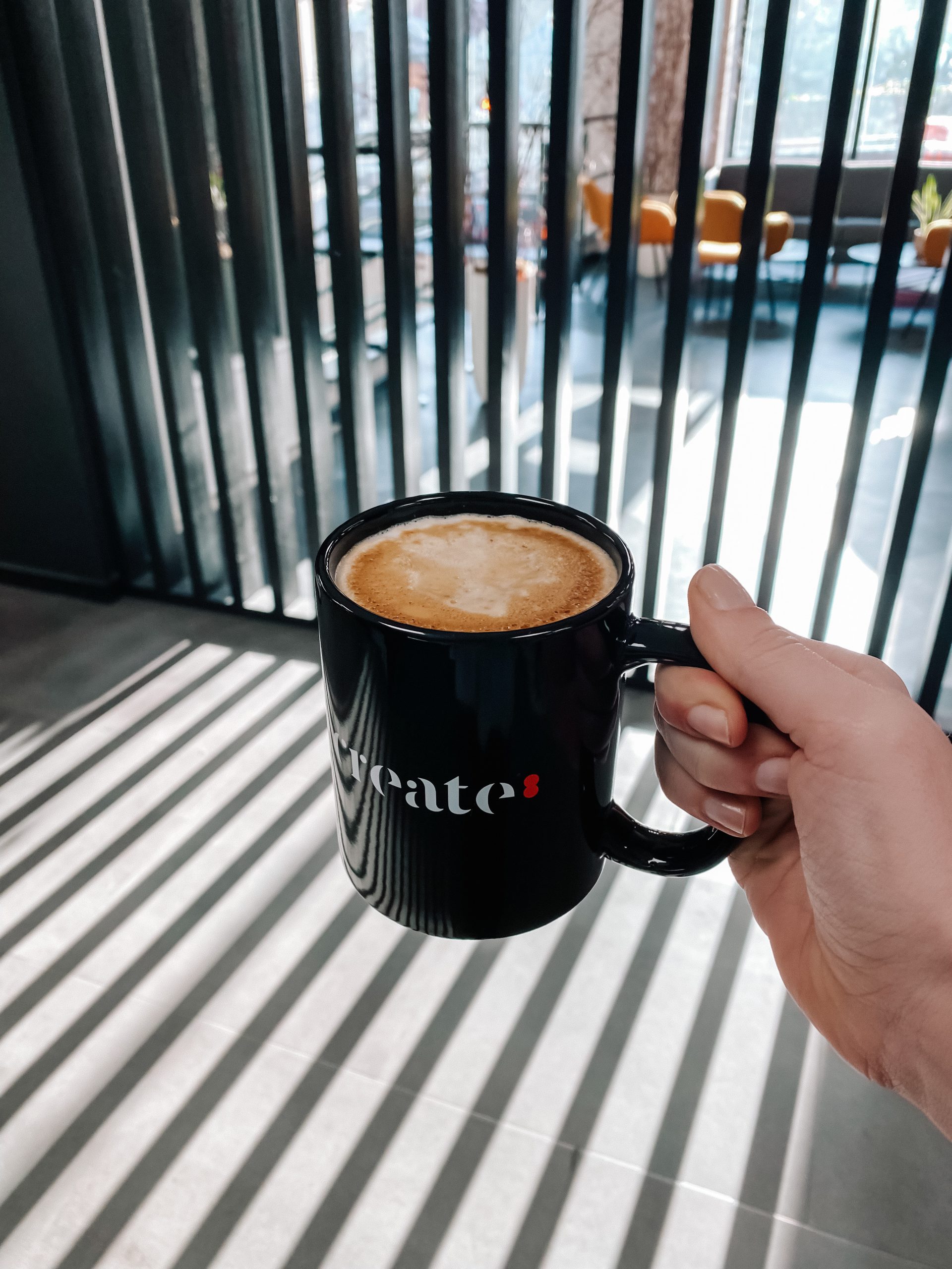 Cup of coffee with Create8 Shopify Agency logo on it