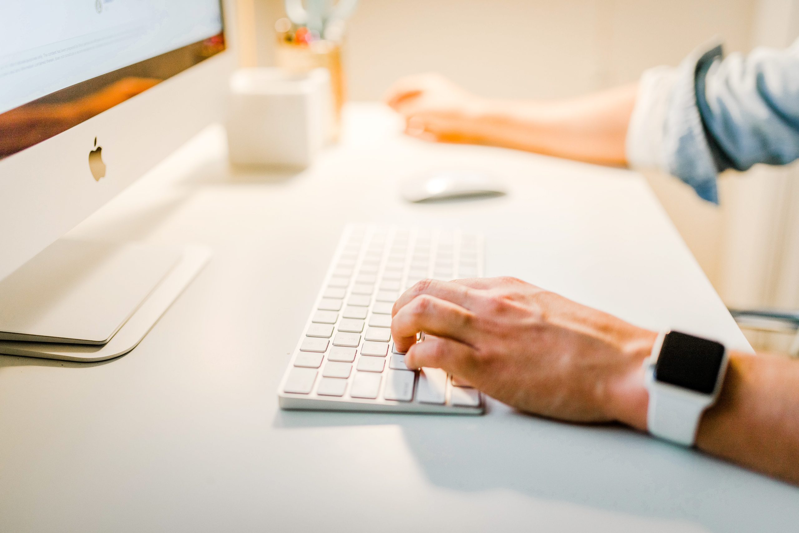 Man sat at desk, working on a desktop computer and setting up an ecommerce store
