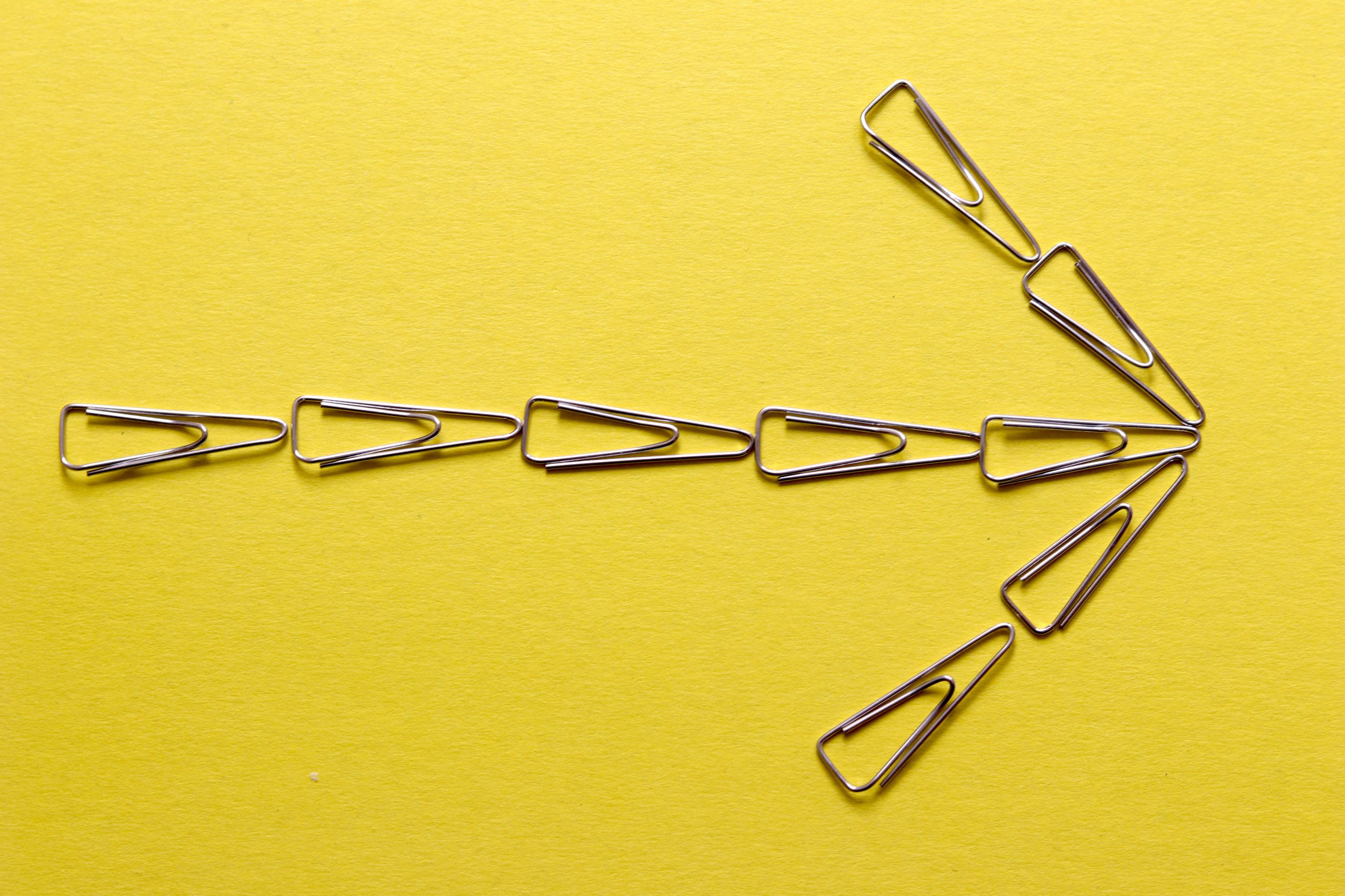paper clips on a yellow background in the shape of a cursor