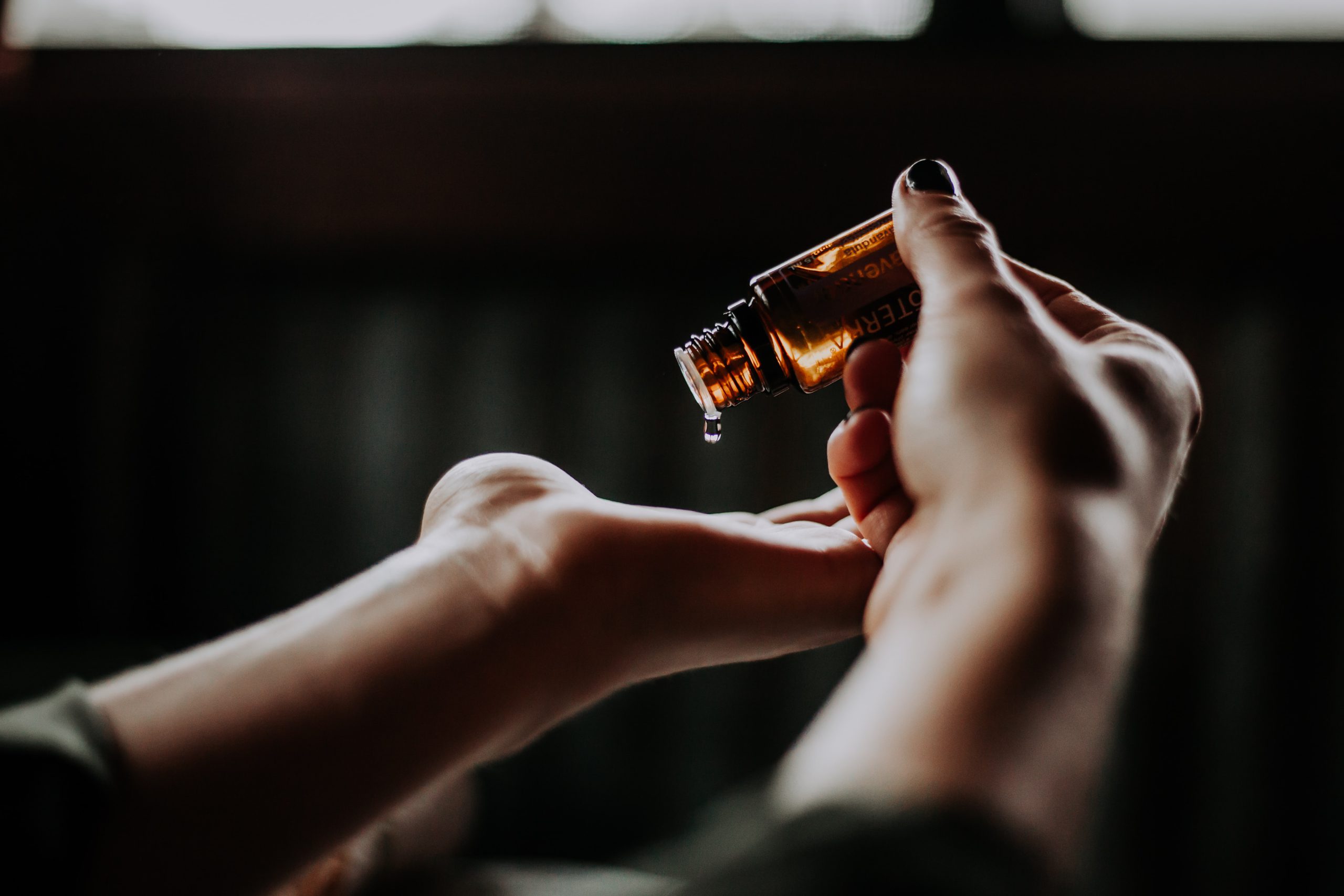 Beauty product being poured into a hand from a glass bottle