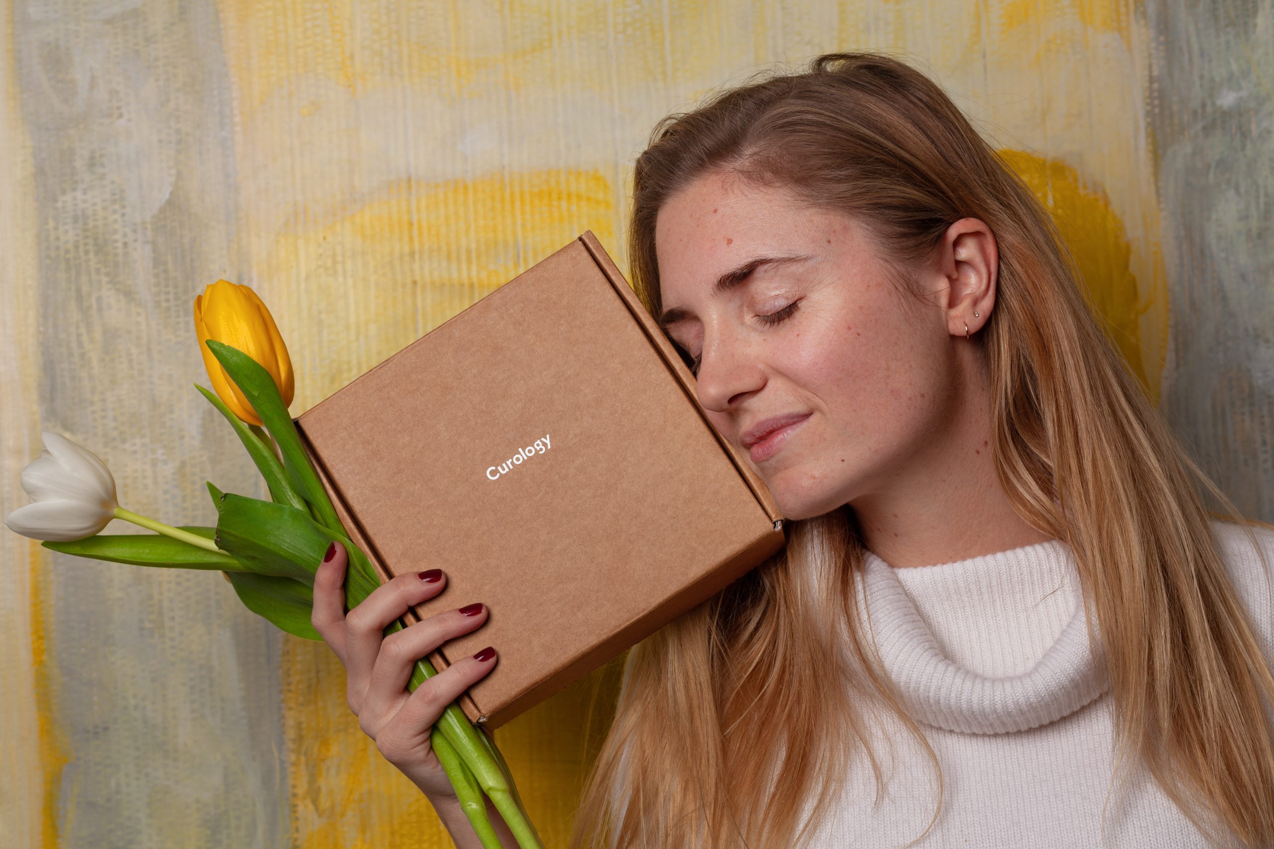 Women holding a beauty subscription box and some yellow and white tulips