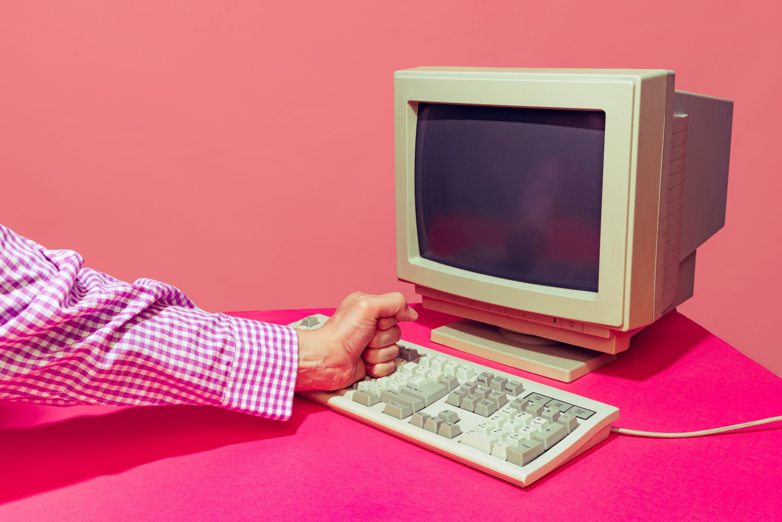 outdated computer against a pink bankground