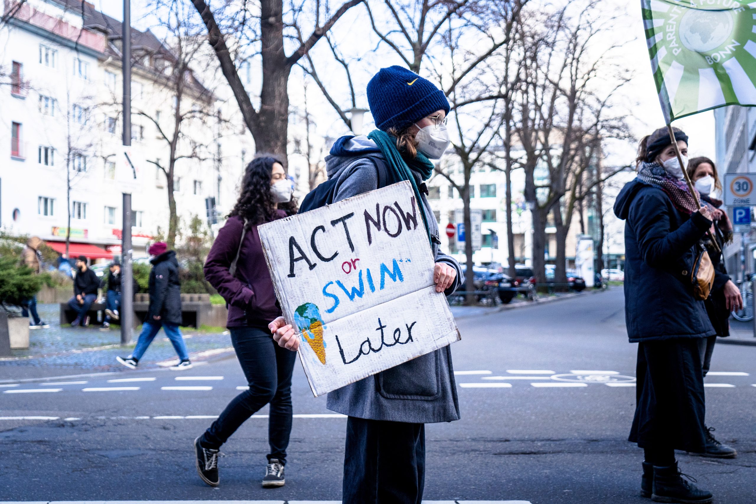 Gen Z protestor holding an eco sign which says "Act now or swim later"