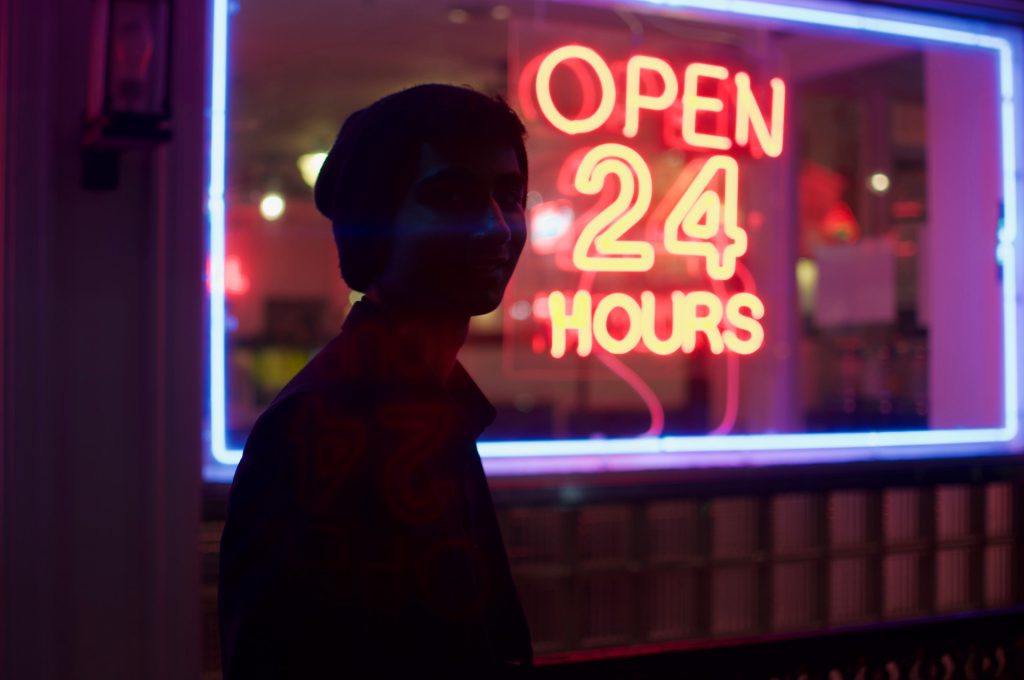 Neon sign in shop window that says "Open 24 Hours"