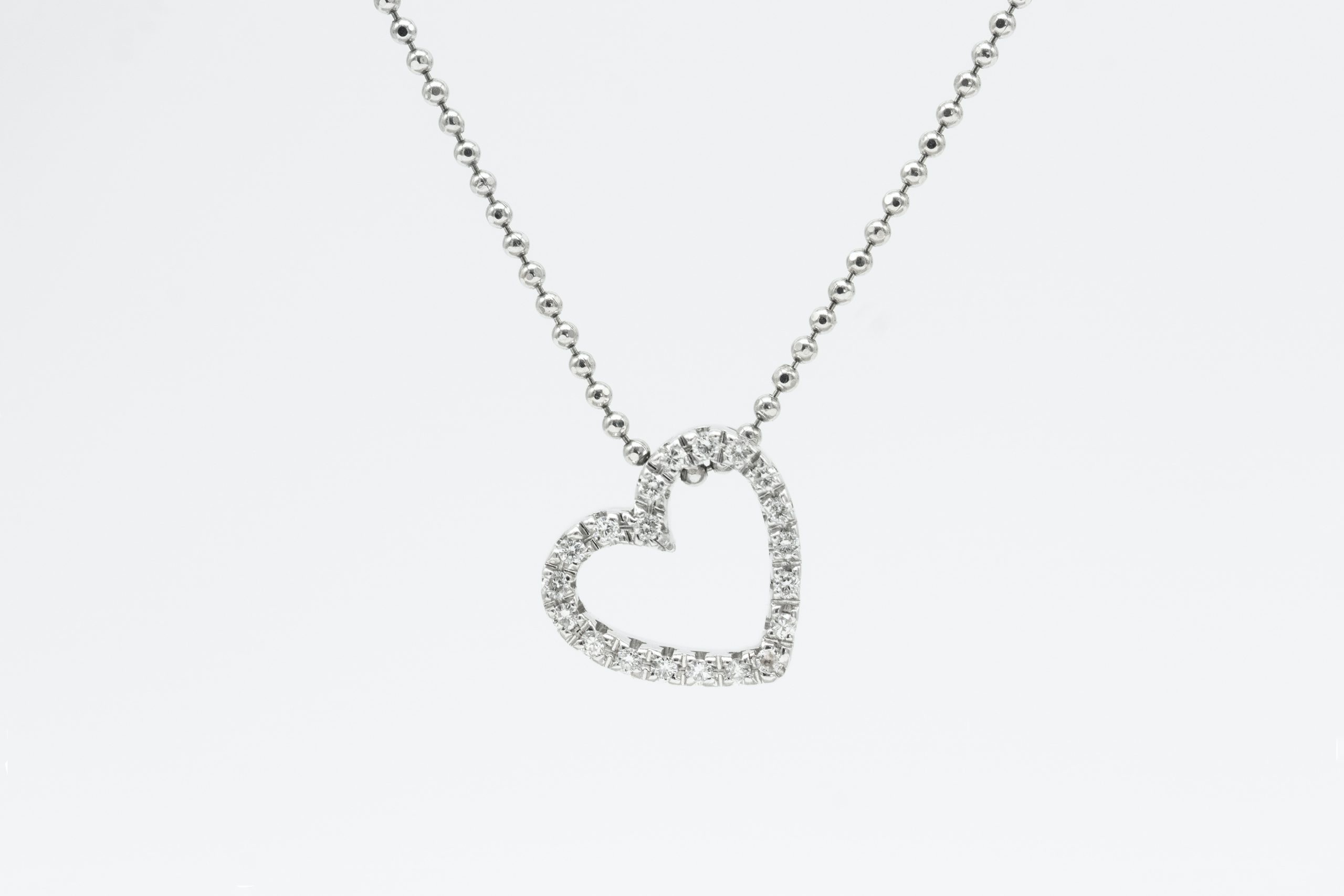 Product photography of a diamond heart necklace against a white background