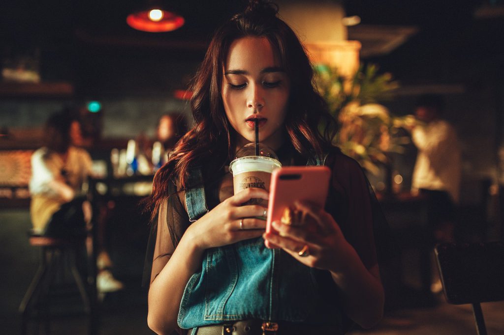 woman shopping on her phone while drinking 